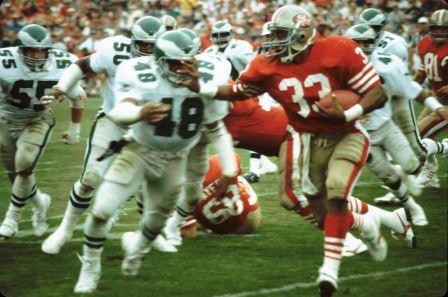 Roger Craig runs past a swarm of Eagles